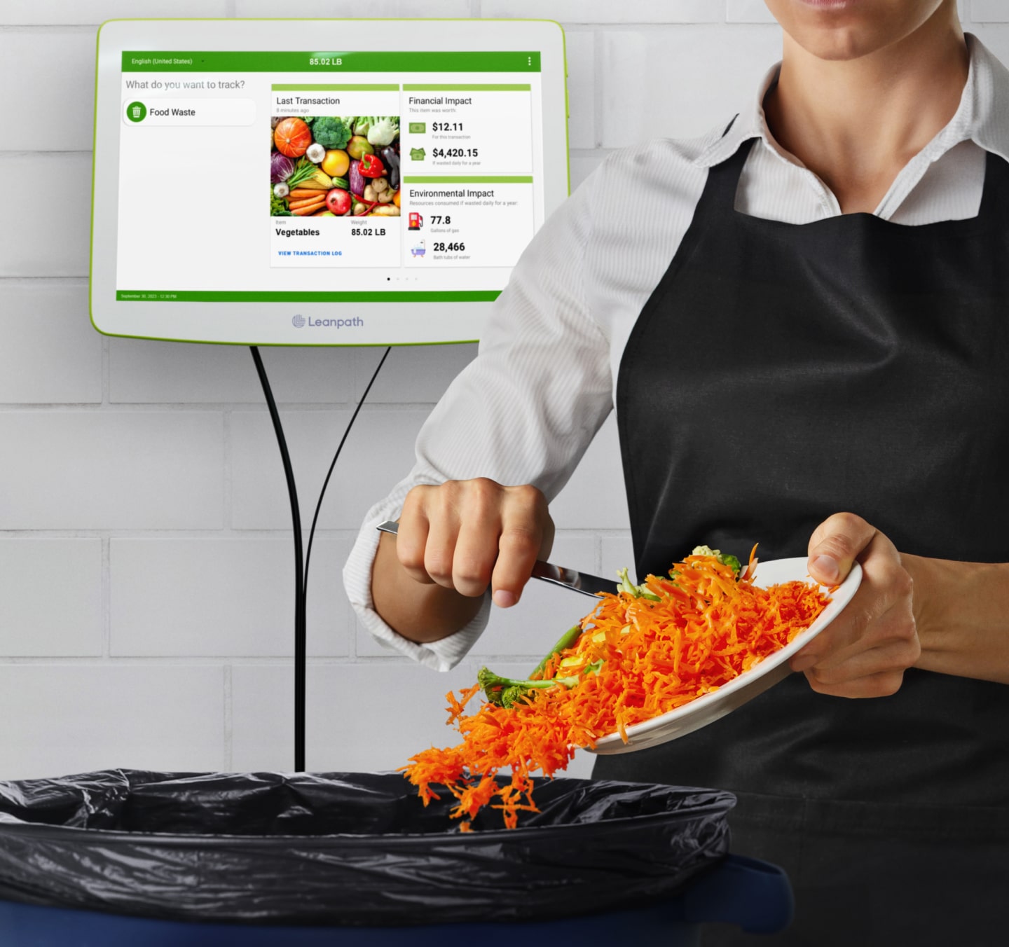 A woman wearing an apron holds a  plate of food, ready to throw it in the trash