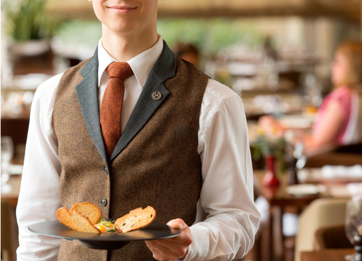 A waiter elegantly holds a tray filled with various dishes, ready to serve guests in a dining setting