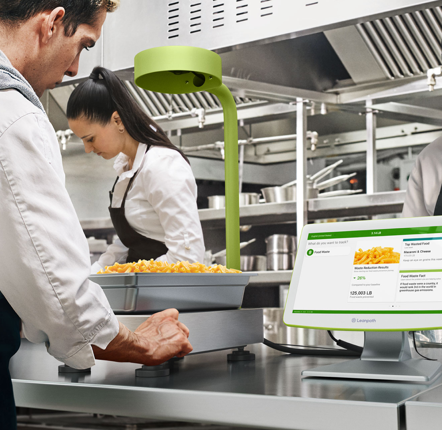 A man and woman chefs collaborate in a kitchen, using a computer and scale for their tasks 