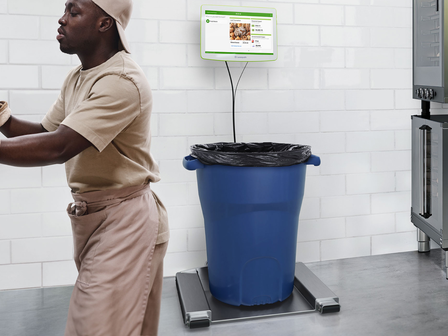 A man in a inoform stands beside a trash can