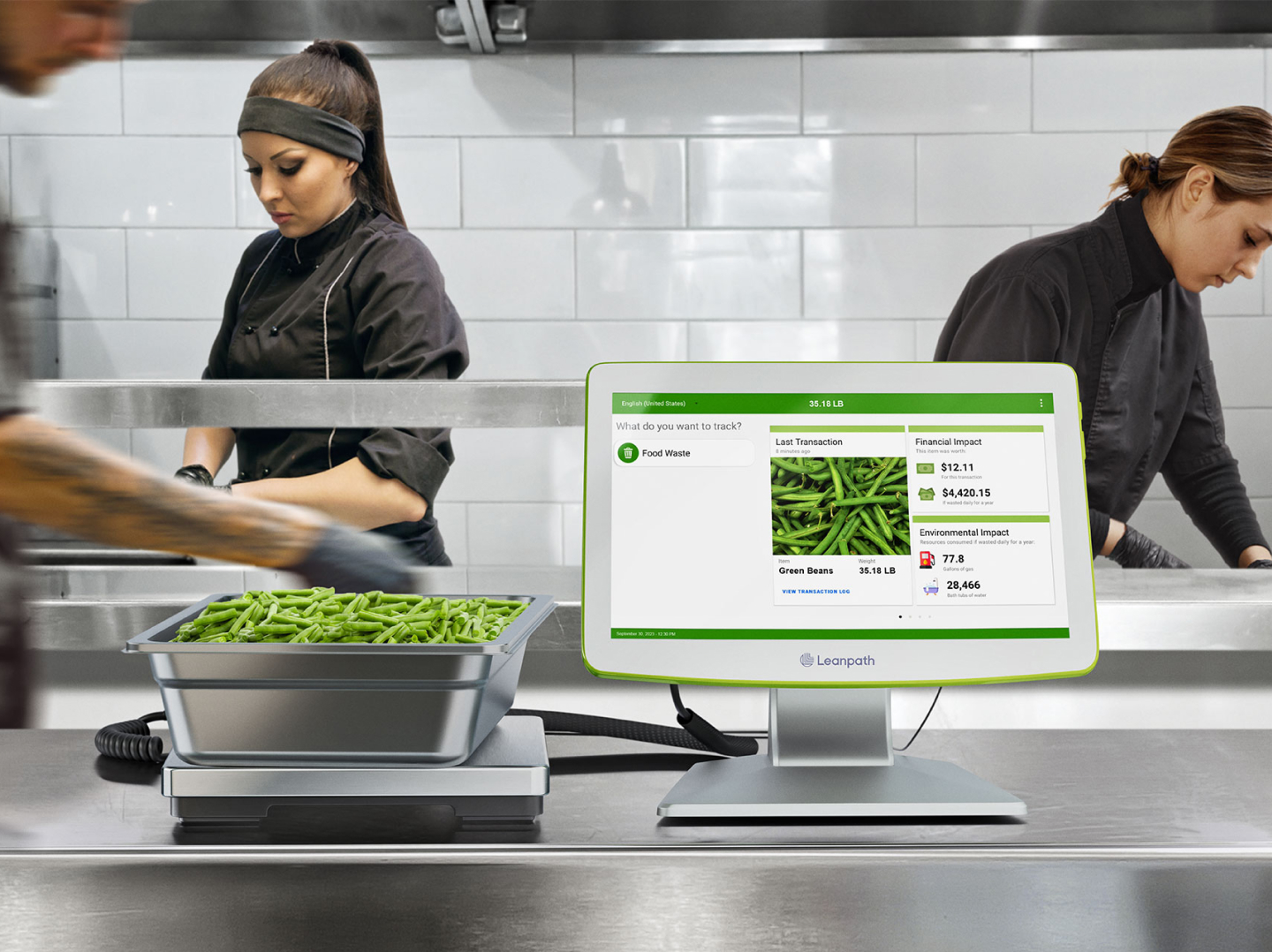 A woman prepares food on a kitchen counter, multitasking with a computer and scale nearby