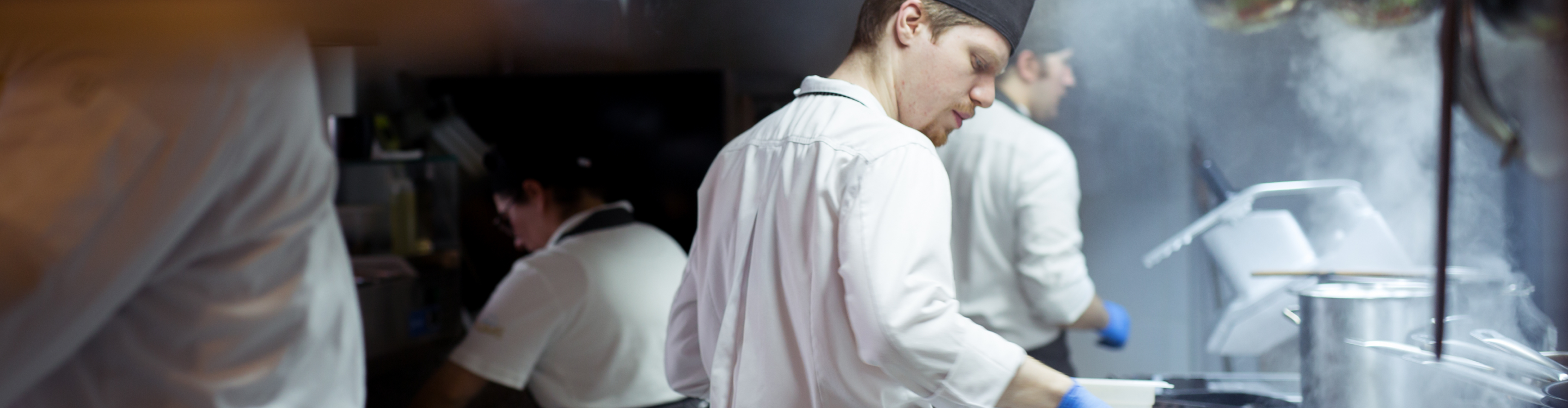 Chefs in a bustling commercial kitchen skillfully preparing various dishes with fresh ingredients and professional equipment