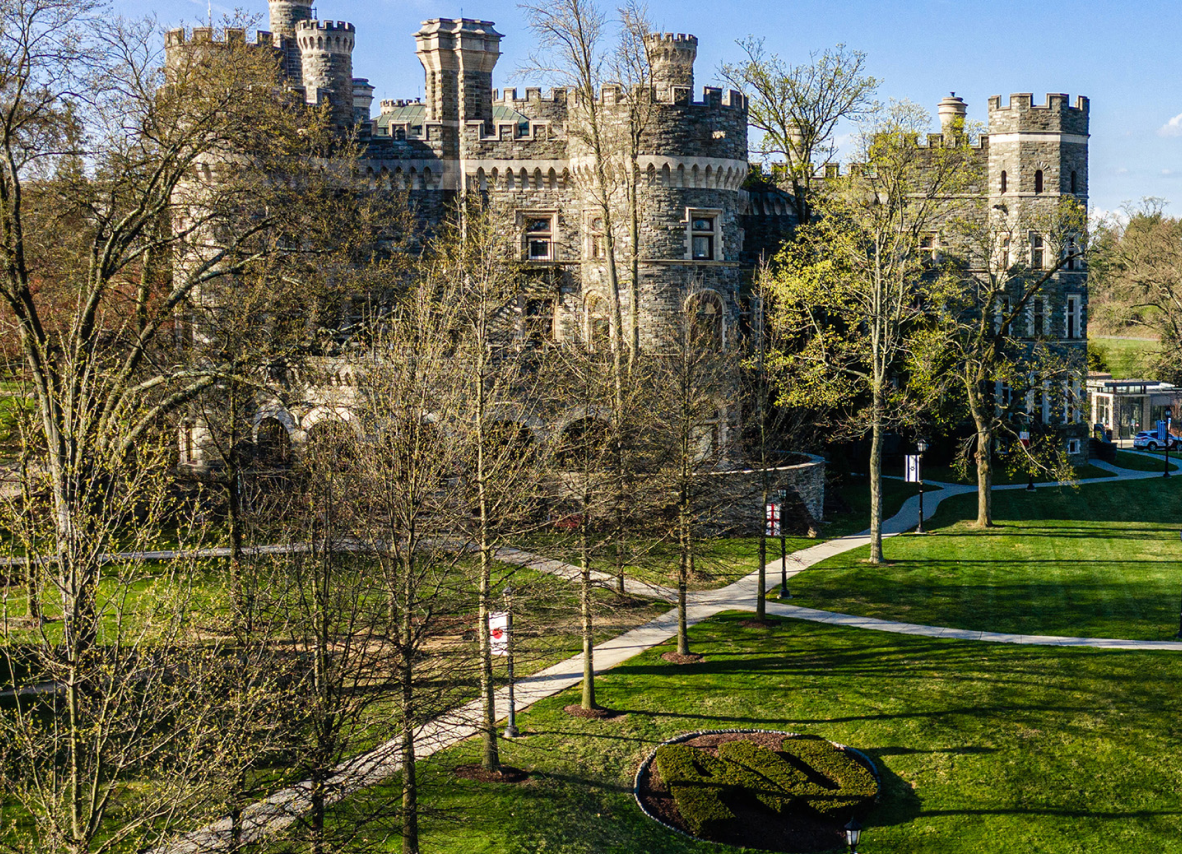 A grand castle atop a hill, providing a scenic view of a vibrant green lawn below