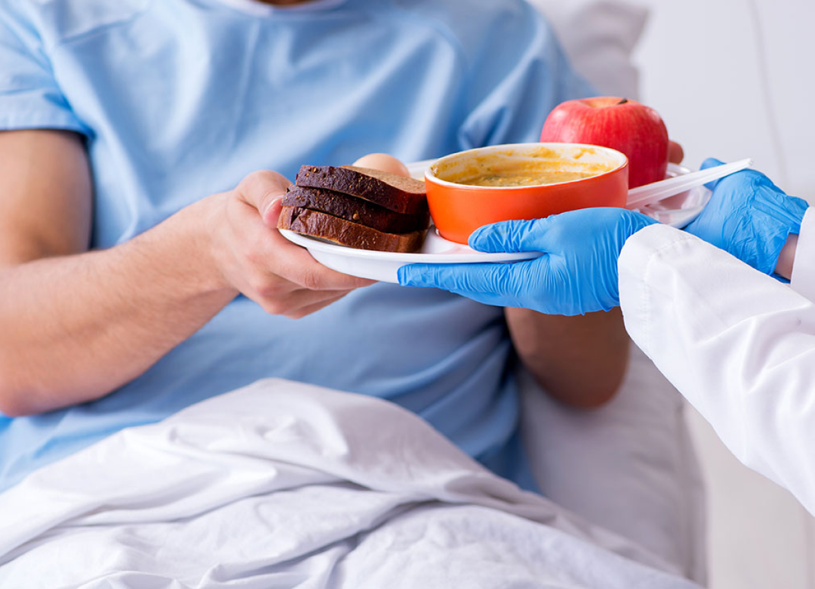 A doctor offers food to a patient in bed